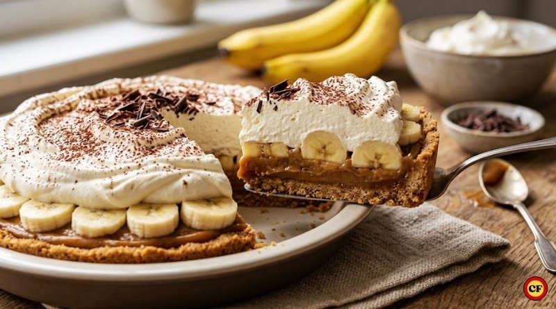 Fotografia profissional de uma torta Banoffee em close, mostrando camadas de base de biscoito, doce de leite, bananas fatiadas e chantilly com raspas de chocolate sobre uma mesa de madeira.