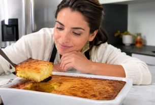 Bolo de fubá cremoso dourado sendo servido enquanto uma mulher observa a textura cremosa
