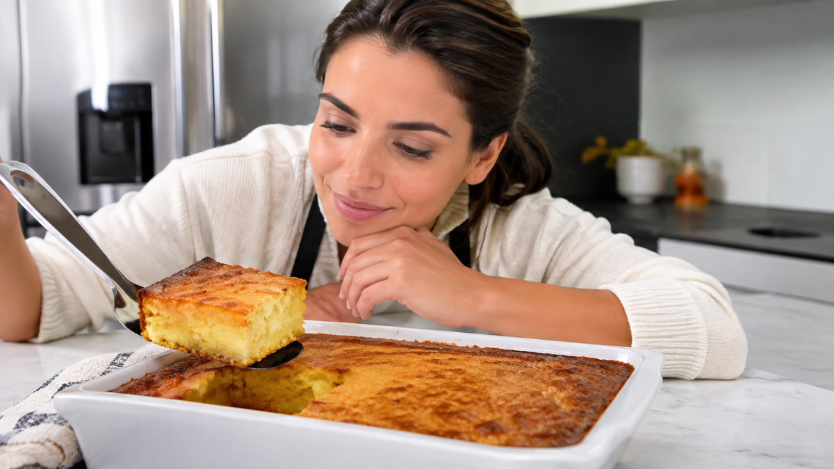 Bolo de fubá cremoso dourado sendo servido enquanto uma mulher observa a textura cremosa